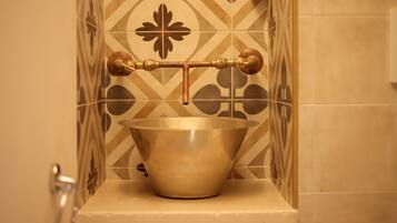 A bathroom with a decorative brass faucet mounted on a tiled wall.