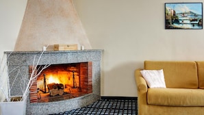 A cozy living room with a stone fireplace, a yellow sofa, and a framed painting on the wall. - Casa Maradona (Massa Lubrense)