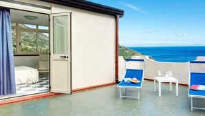 A balcony with a bed, two lounge chairs, and a table with drinks. - Casa Maradona (Massa Lubrense)