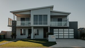 Una casa moderna de dos pisos con garaje, balcón y césped bien cuidado.