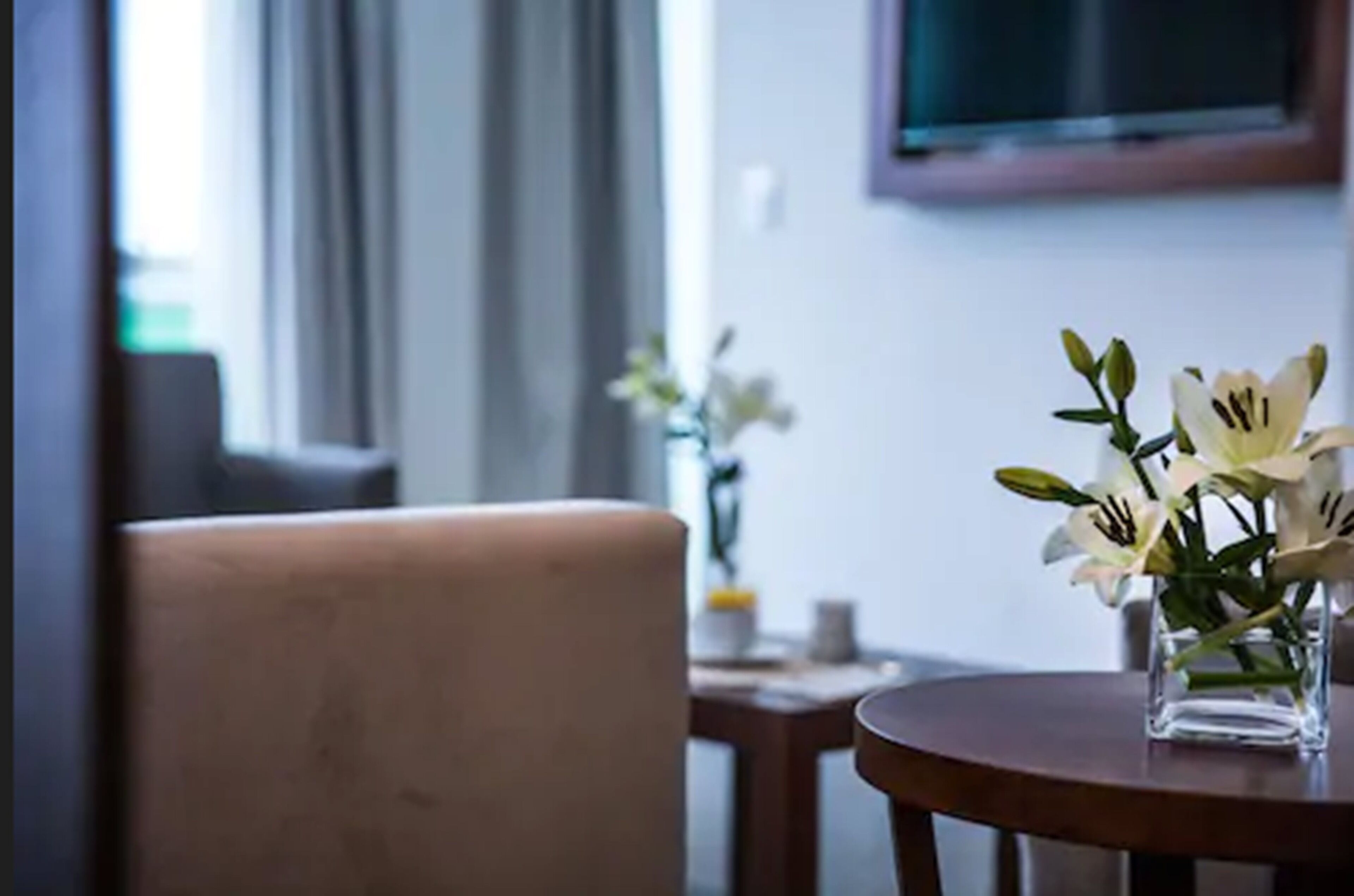 Una habitación con una mesa redonda, una silla y un florero con flores blancas.