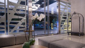 Un vestíbul modern amb zones d'estar, una orquídia en test i vista al carrer.