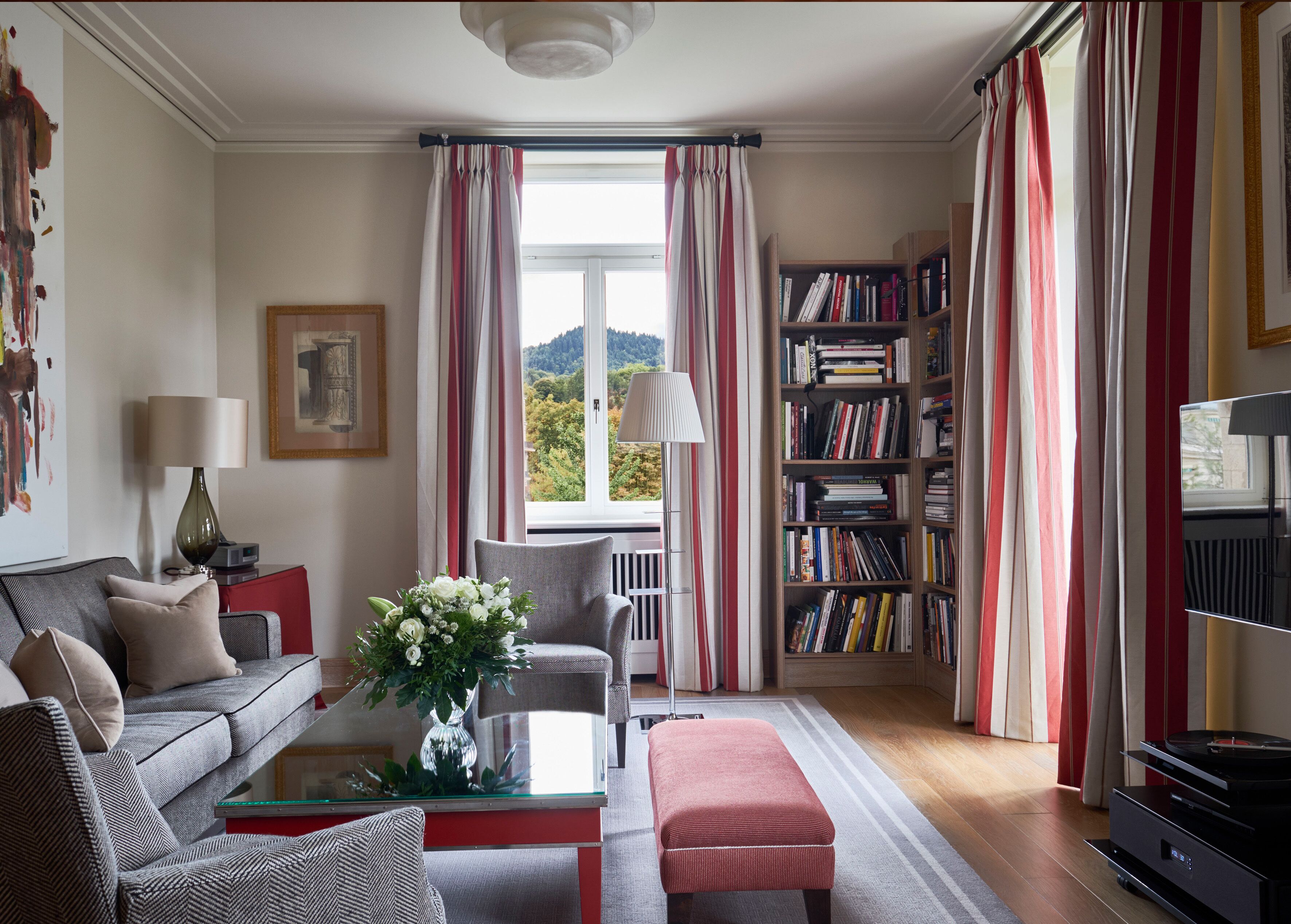 A living room with a sofa, a coffee table with a vase, a bookshelf, and a TV.
