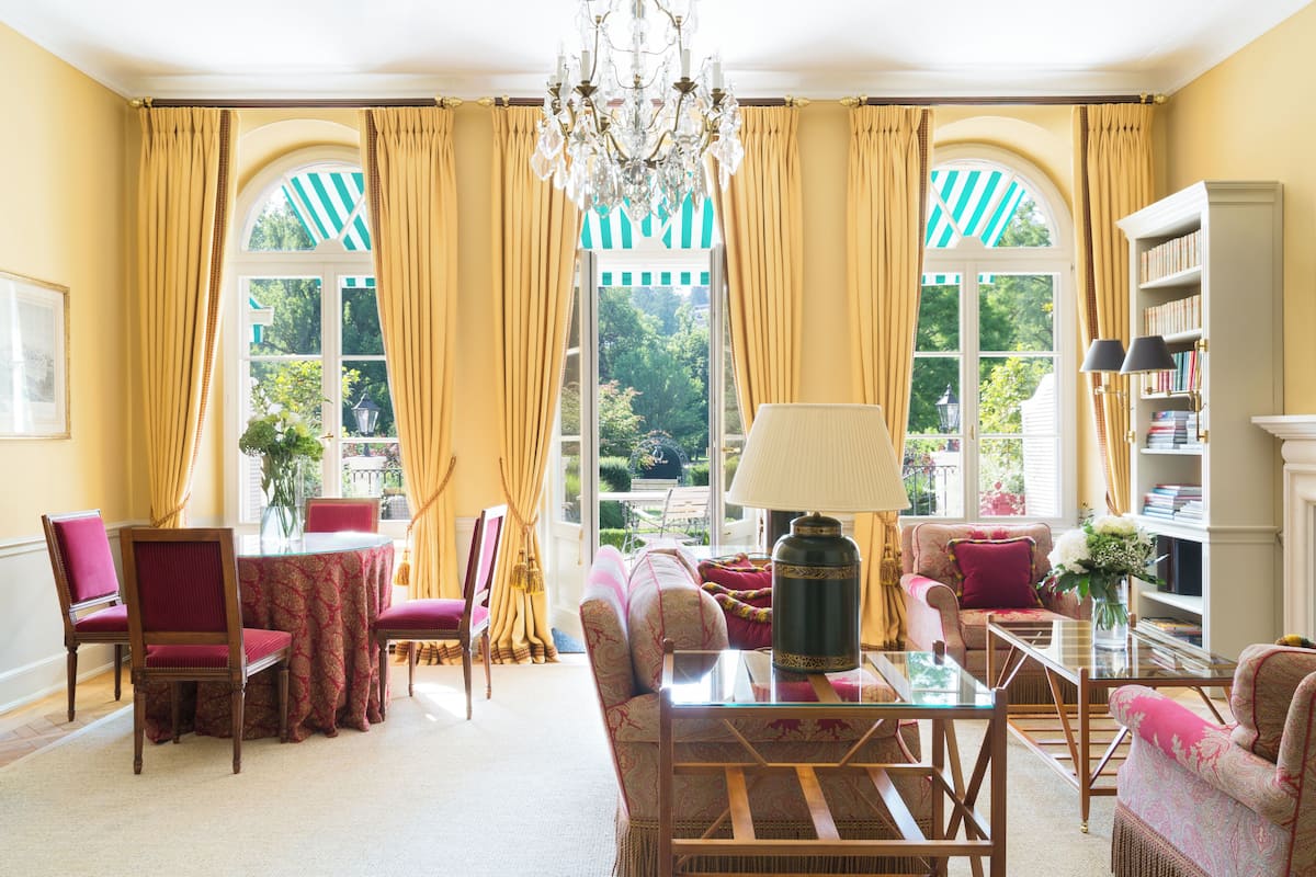A room with a large window, a chandelier, and a bookshelf.