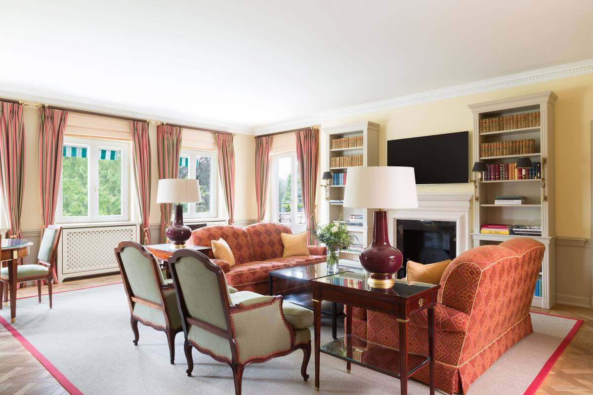 A living room with a sofa set, armchairs, a coffee table, a fireplace, and a bookshelf.