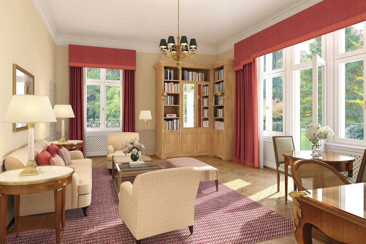 A spacious living room with a large bookshelf, a comfortable sofa, a coffee table, and a dining area with chairs.