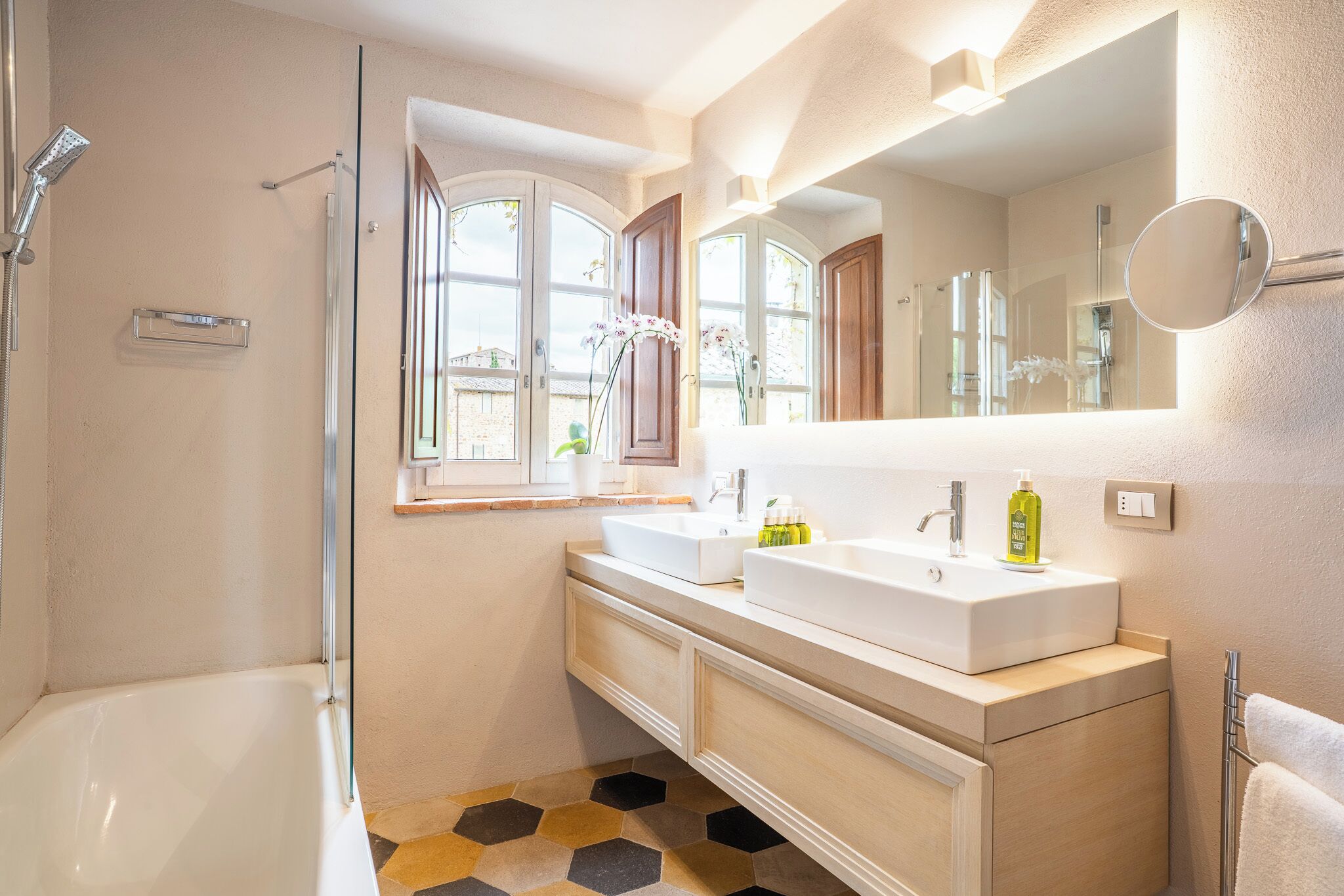 Une salle de bain moderne avec une baignoire, deux lavabos, un grand miroir et une douche.