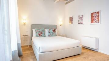 A bedroom with a bed, bedside tables, wall-mounted artwork, and a radiator.