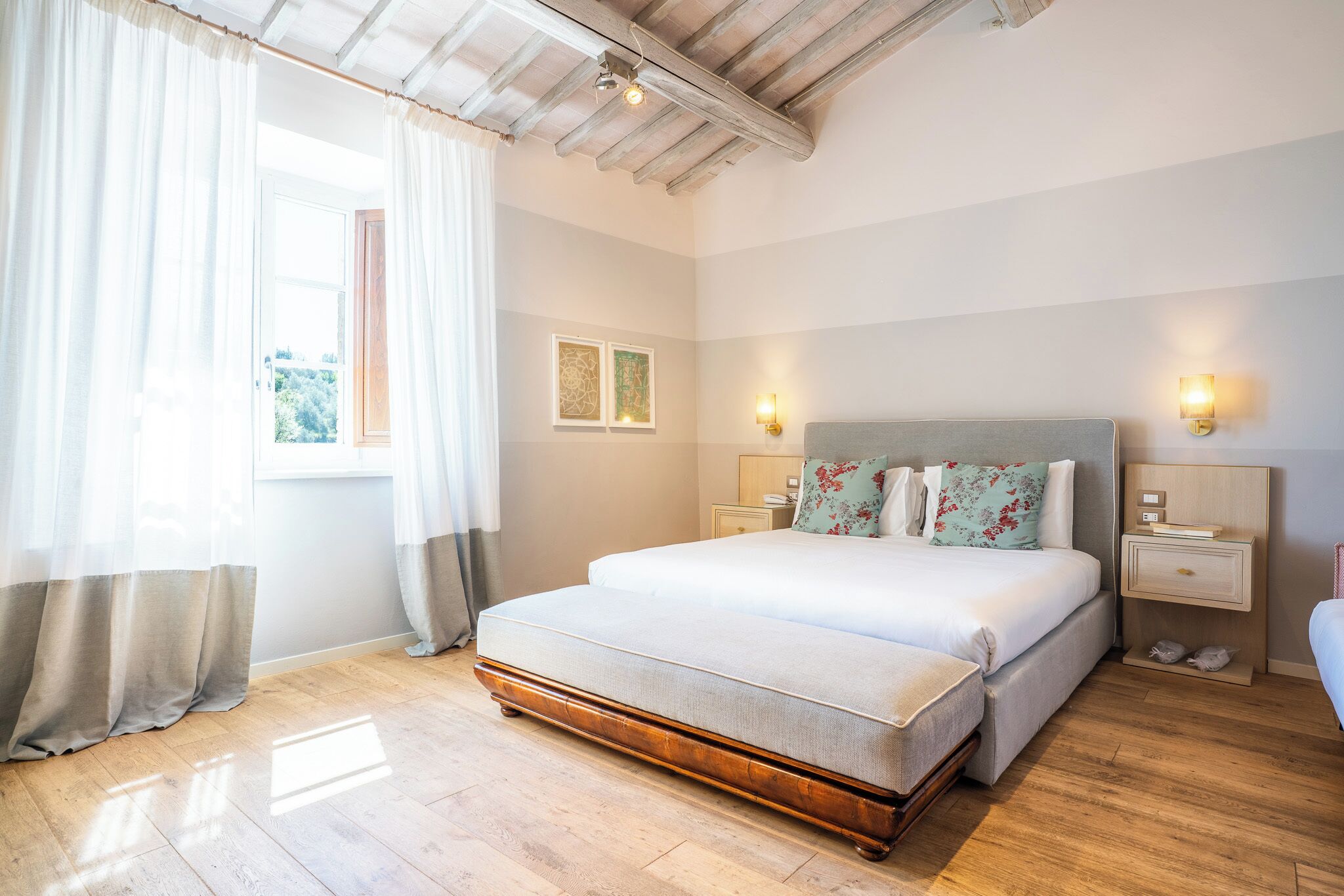 A bedroom with a large bed, bedside tables, a nightstand, and a window with curtains.