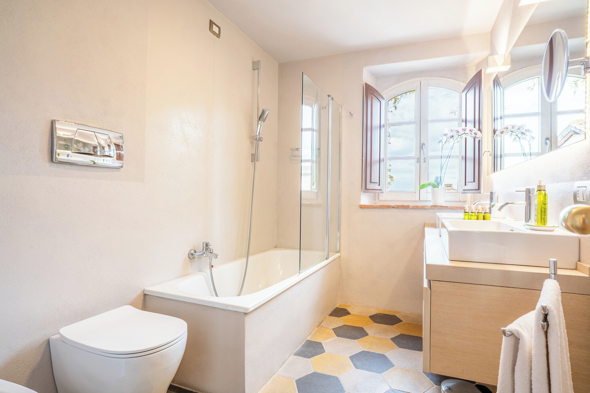 Un baño con inodoro, bañera, ducha y lavamanos con espejo.