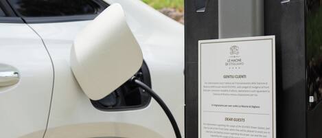 A charging station with a sign for Le Macine di Stigliano, indicating it is an EV charging station.