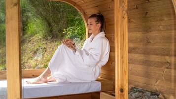 Una sauna in legno con una panchina, una finestra e un piccolo vassoio con pietre.