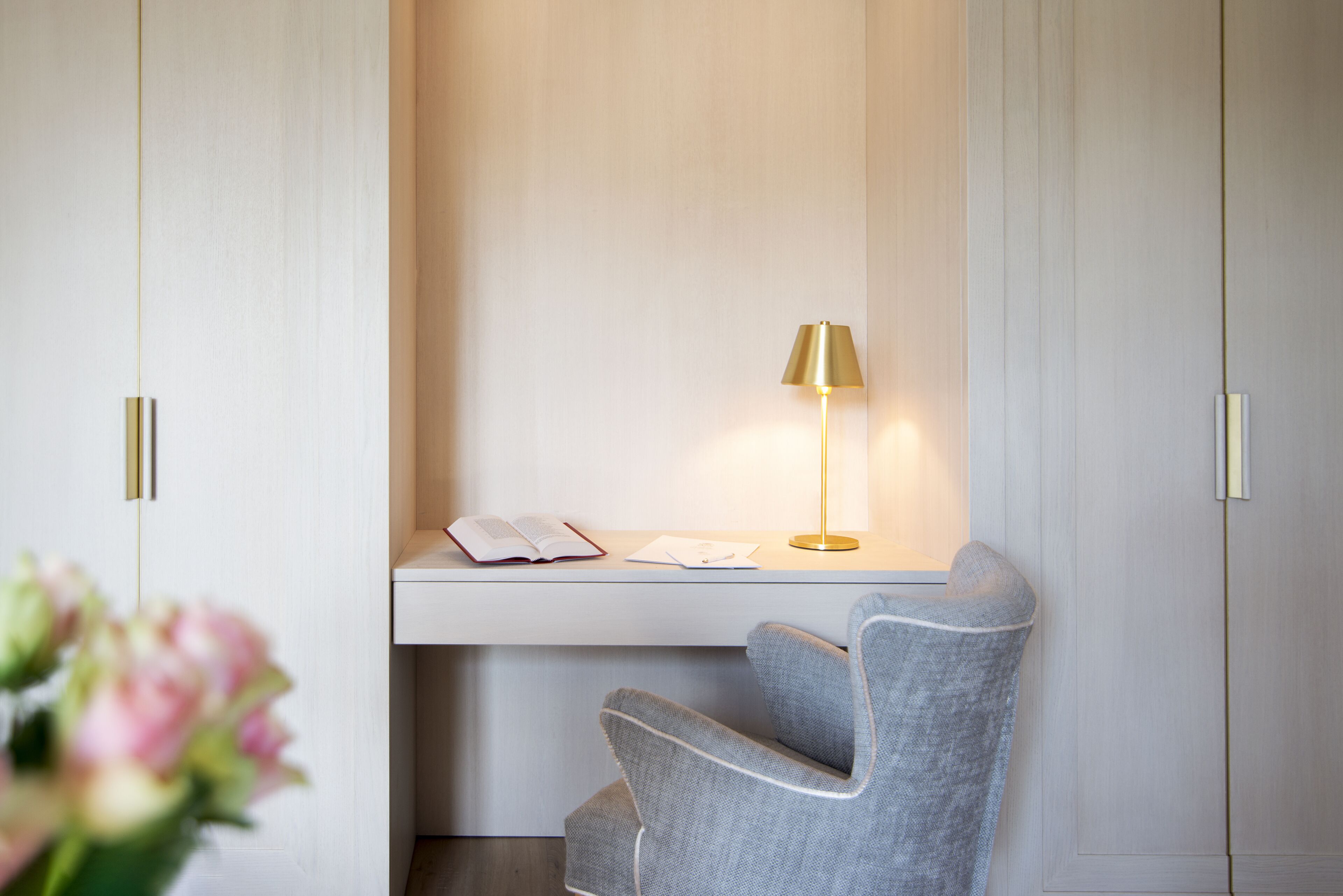A modern desk with a lamp, a chair, and a book on the desk.