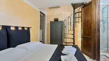 A hotel room with a bed, a wardrobe, a shower area, and a staircase.