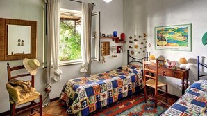 Ein gemütliches Schlafzimmer mit Bett, Stuhl, Schreibtisch und einem fenster mit Vorhängen.