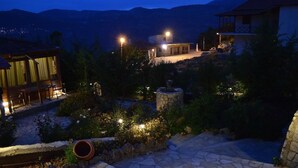 Un patio con suelo de piedra, una terraza de madera y una fuente de piedra.
