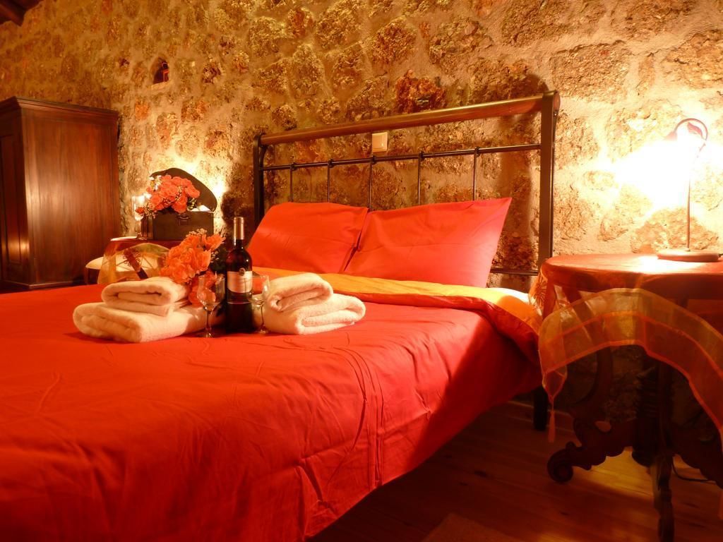 Una cama con una colcha roja, un cabecero de madera y una mesita de noche con una lámpara.