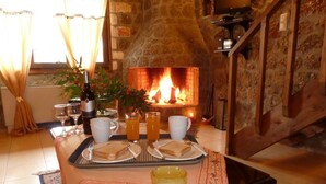 Un comedor acogedor con chimenea, una mesa dispuesta con sándwiches, vasos y una botella de vino.