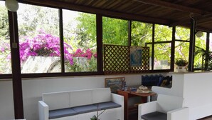 A covered outdoor seating area with wicker furniture, a small table, and a potted plant. - Residence Missipezza (Otranto)