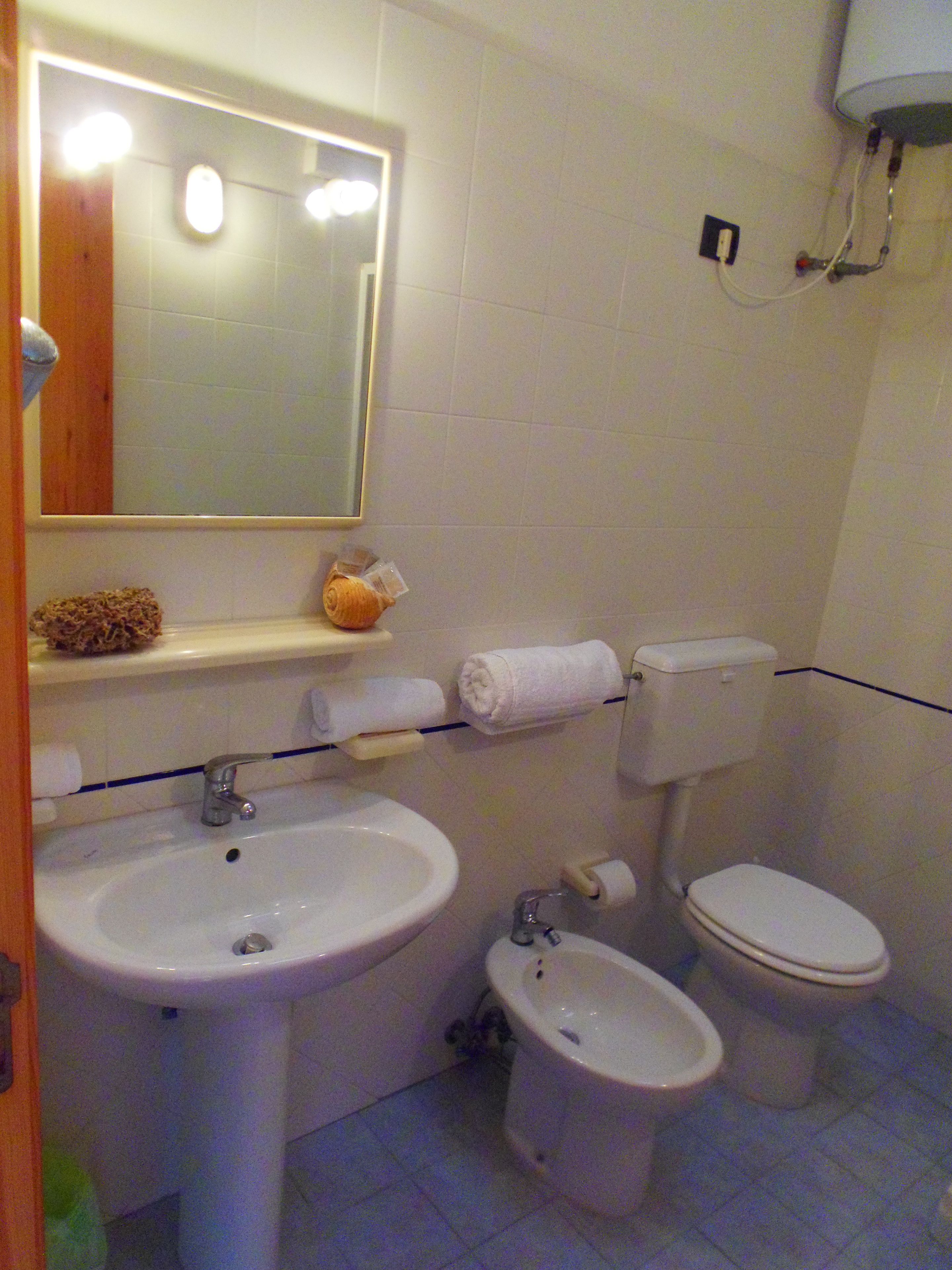 Une salle de bain équipée d’un lavabo, d’un bidet, de toilettes et d’un miroir avec éclairage.