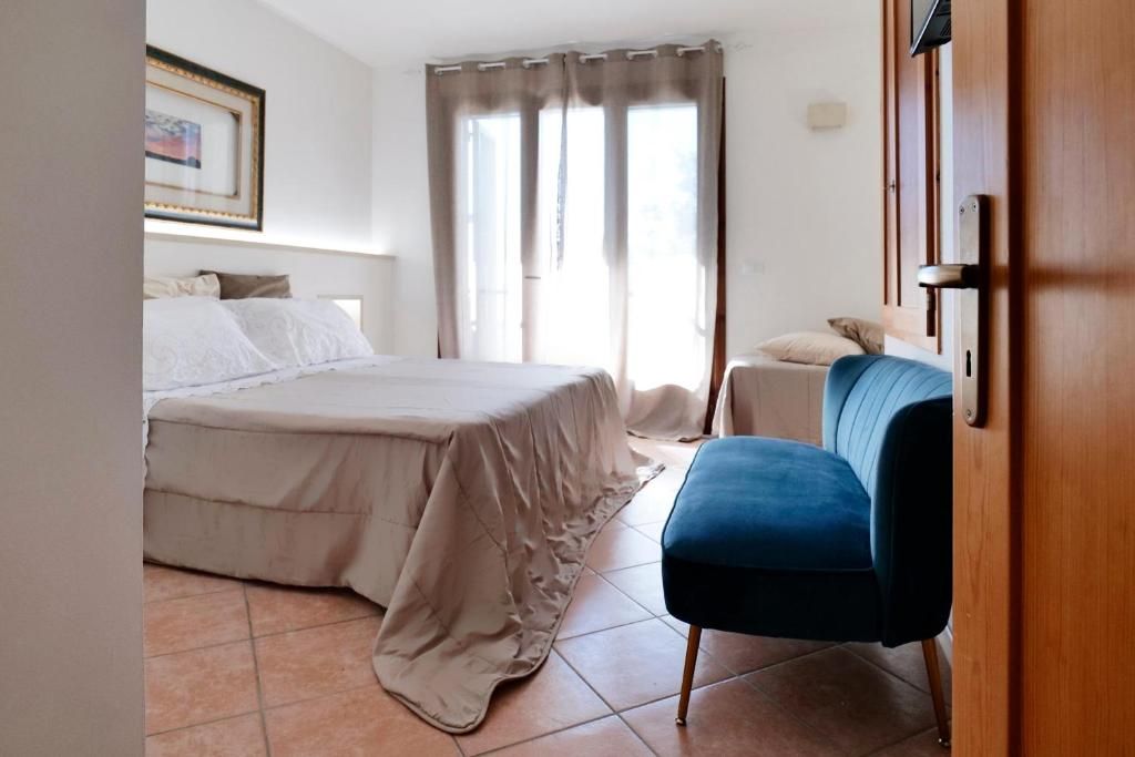 A bedroom with a bed, a chair, a window with curtains, and a door.