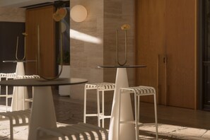 A modern interior with white chairs and tables, wooden doors, and a marble floor. - The Calile Hotel (Fortitude Valley)