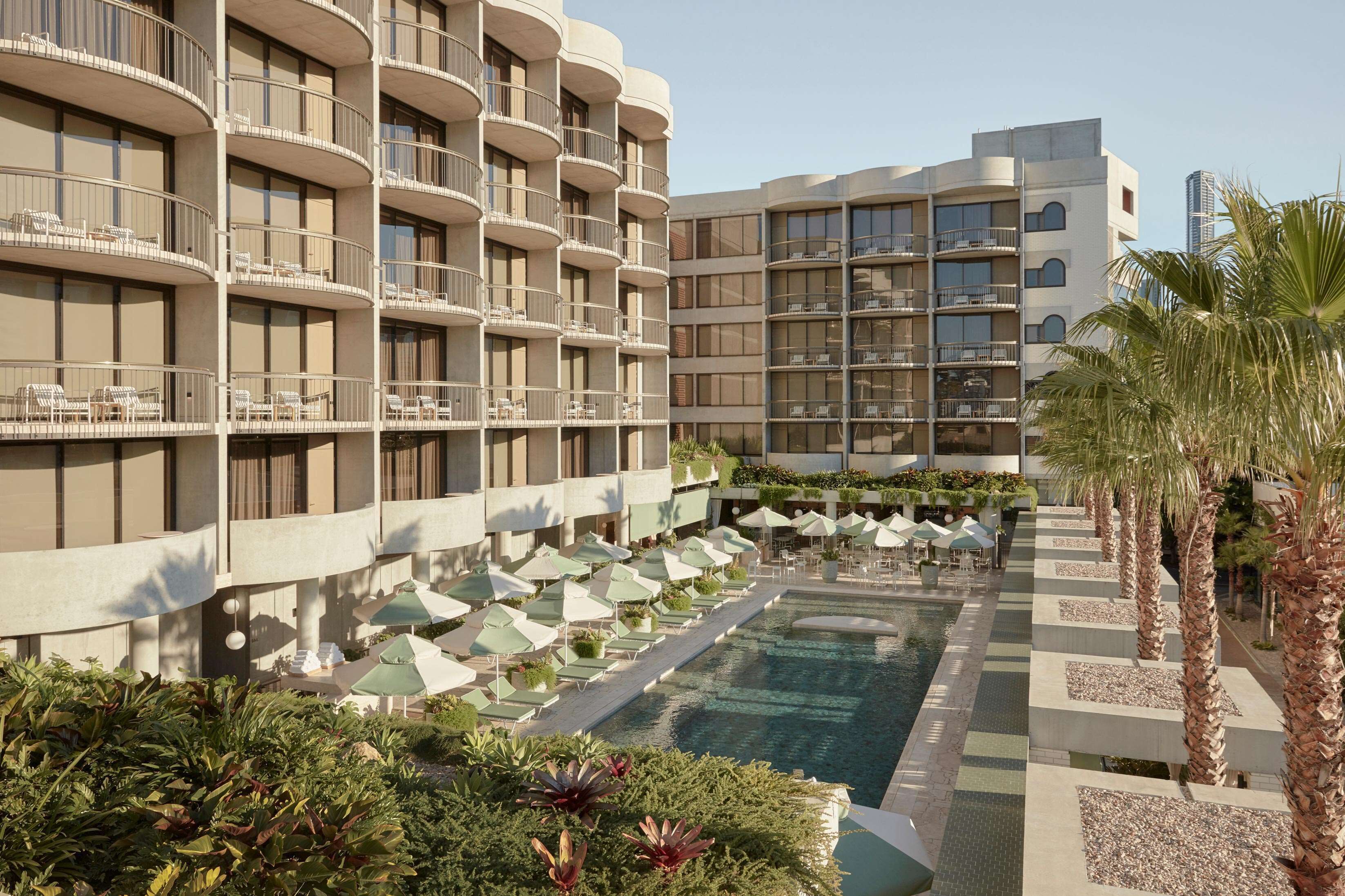 A hotel with multiple balconies, a swimming pool, and outdoor seating areas.