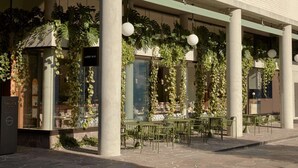 A multi-story building with a covered outdoor seating area, columns, and greenery. - The Calile Hotel (Fortitude Valley)