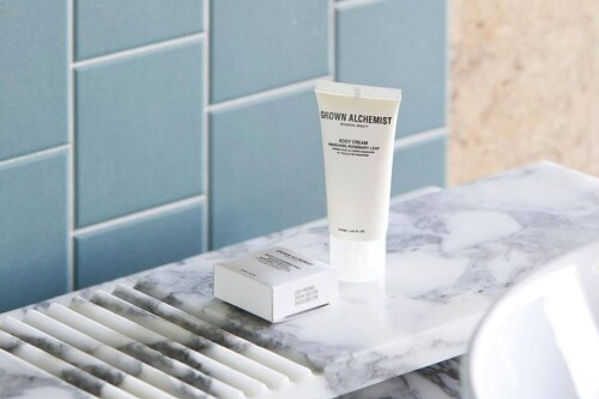 A bathroom with a marble sink, a white tube of body cream, and a white box on the counter.