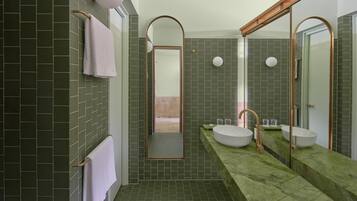 A modern bathroom with green tiles, two sinks, and a large mirror.