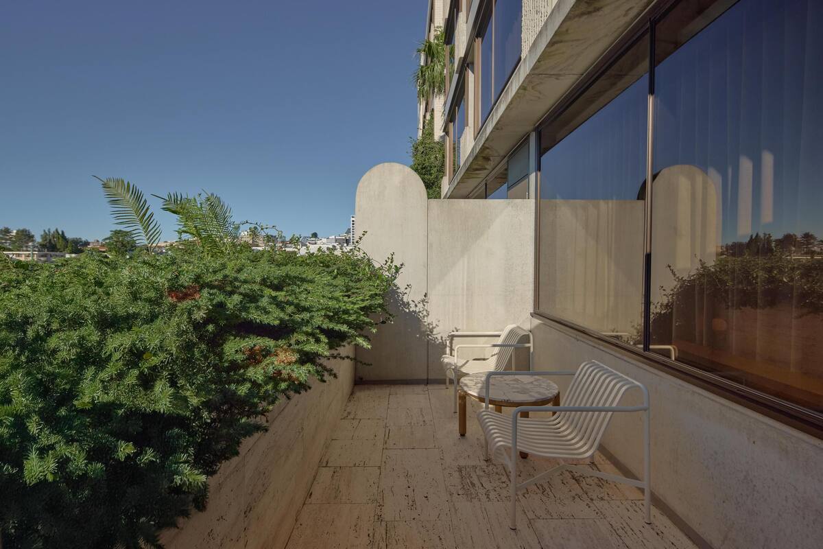A balcony with a seating area, a large window, and a view of the cityscape.