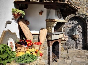 Cocina exterior con horno de piedra, utensilios de madera y productos frescos.
