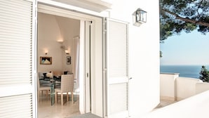A coastal property with a dining area featuring a table and chairs, a view of the sea, and a balcony with a railing. - Villa Bougainvillea (Capri)