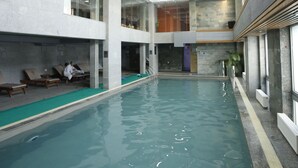 Una piscina interior con agua cristalina, un techo con iluminación empotrada y una zona de estar con tumbonas.