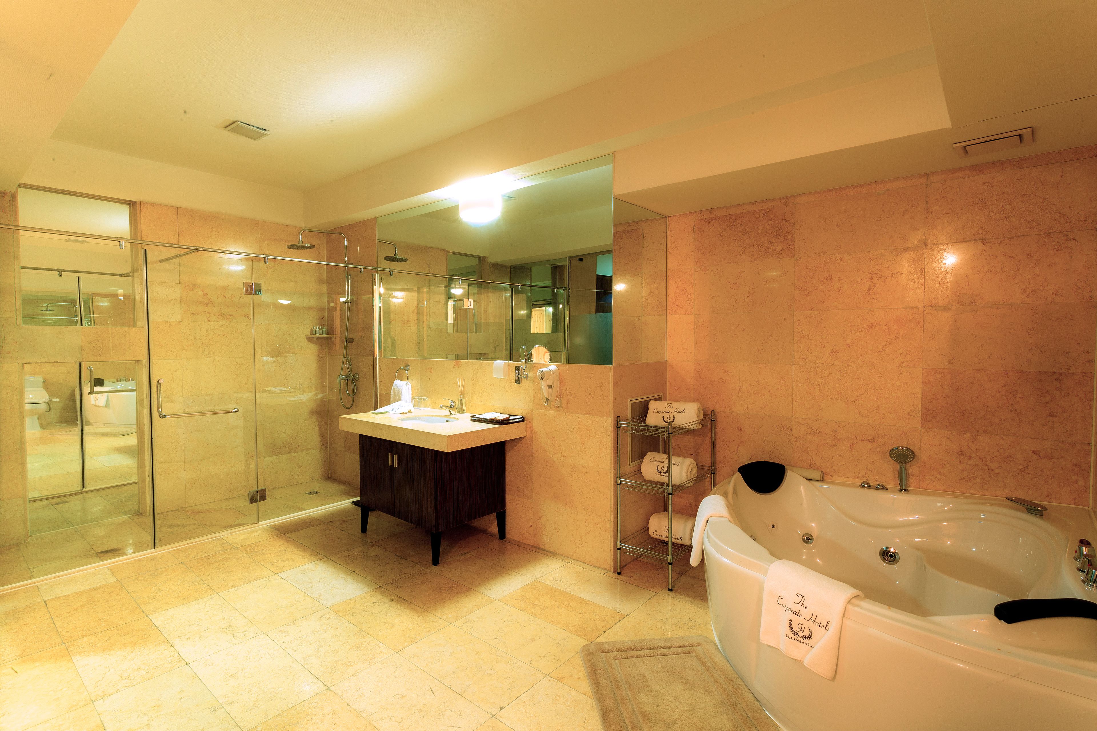 A modern bathroom with a glass-enclosed shower, a vanity with a mirror, and a large bathtub with a towel.