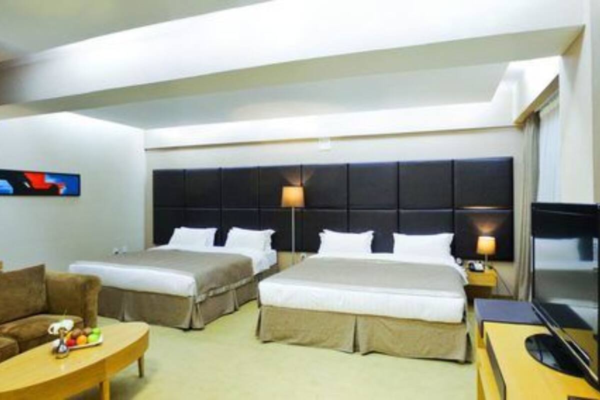 Une chambre d’hôtel avec deux lits, un canapé, une télévision et un tableau au mur.