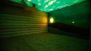 Una habitación con paredes de madera y suelo arenoso, una fuente de luz a la derecha y un techo inclinado.