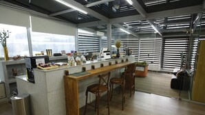 Una cocina moderna con una isla central, taburetes de bar y un cubo de basura de acero inoxidable.