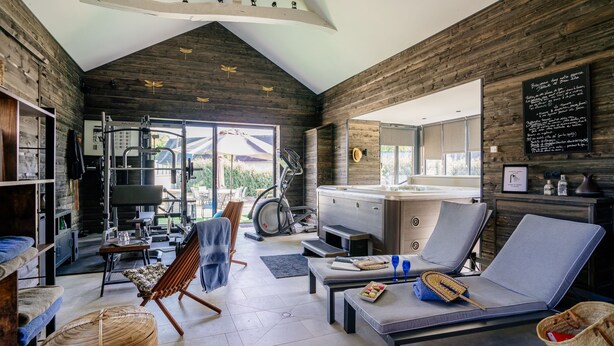 Een moderne woonkamer met een open haard, fitnessapparatuur en een eethoek.