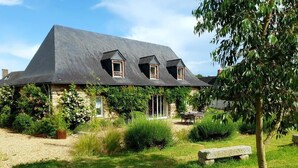 Een stenen huis met een schuin dak en meerdere ramen.