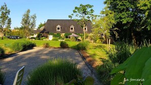 Een ruime woning met een grindpad, omringd door weelderige begroeiing en bomen.