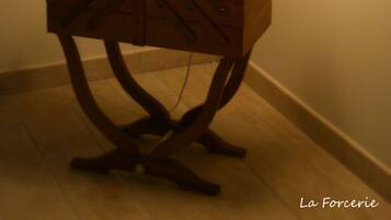A wooden bedside table with a white lamp, a basket, and a small electronic device.