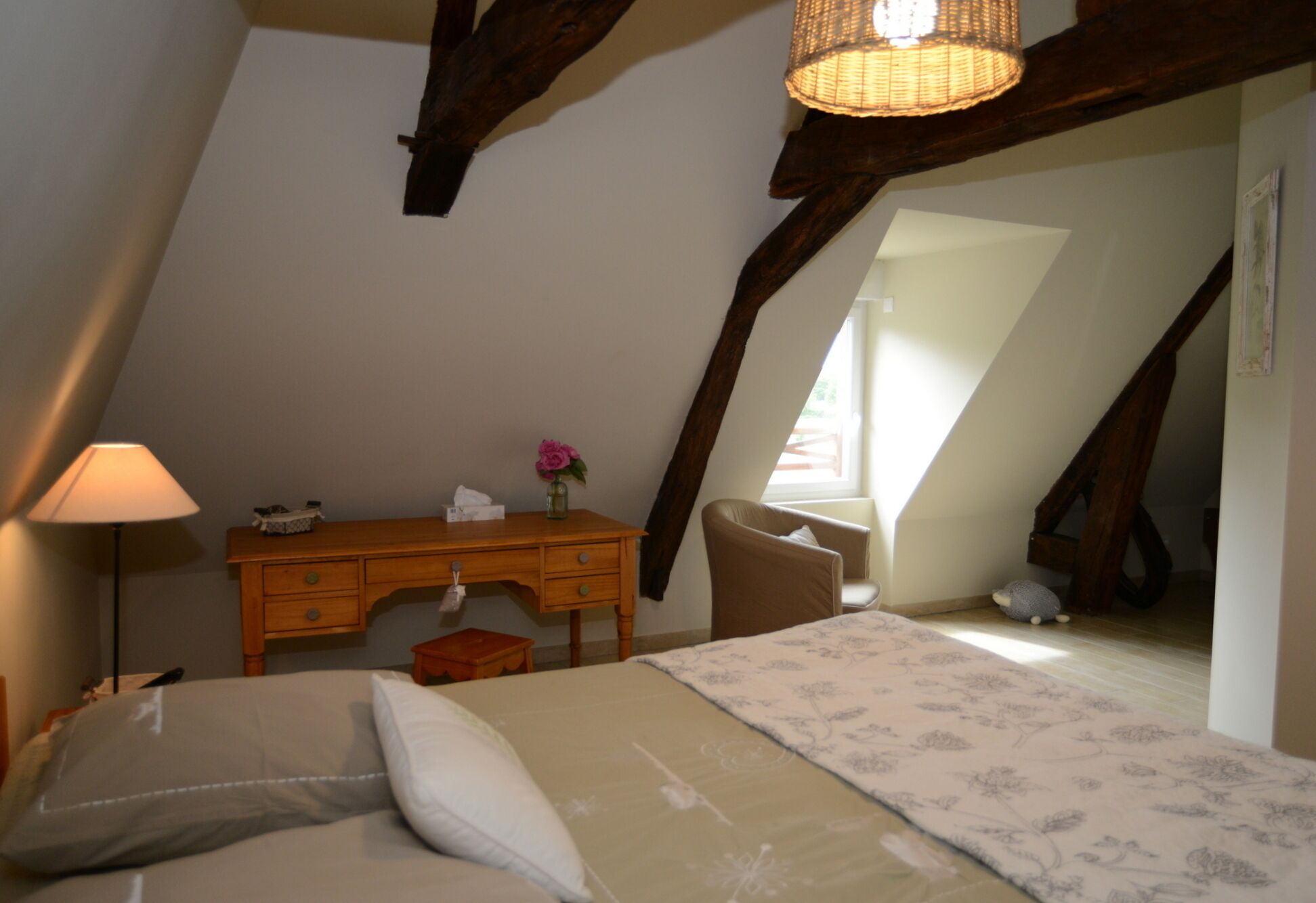 A cozy attic bedroom with a bed, a desk, and a chair.