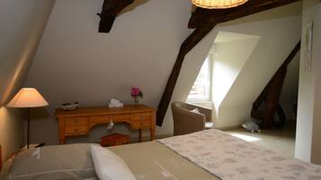 A cozy attic bedroom with a bed, a desk, and a chair.