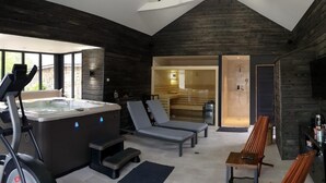 Een moderne spa met een jacuzzi, fitnessapparatuur en lounge fauteuils.