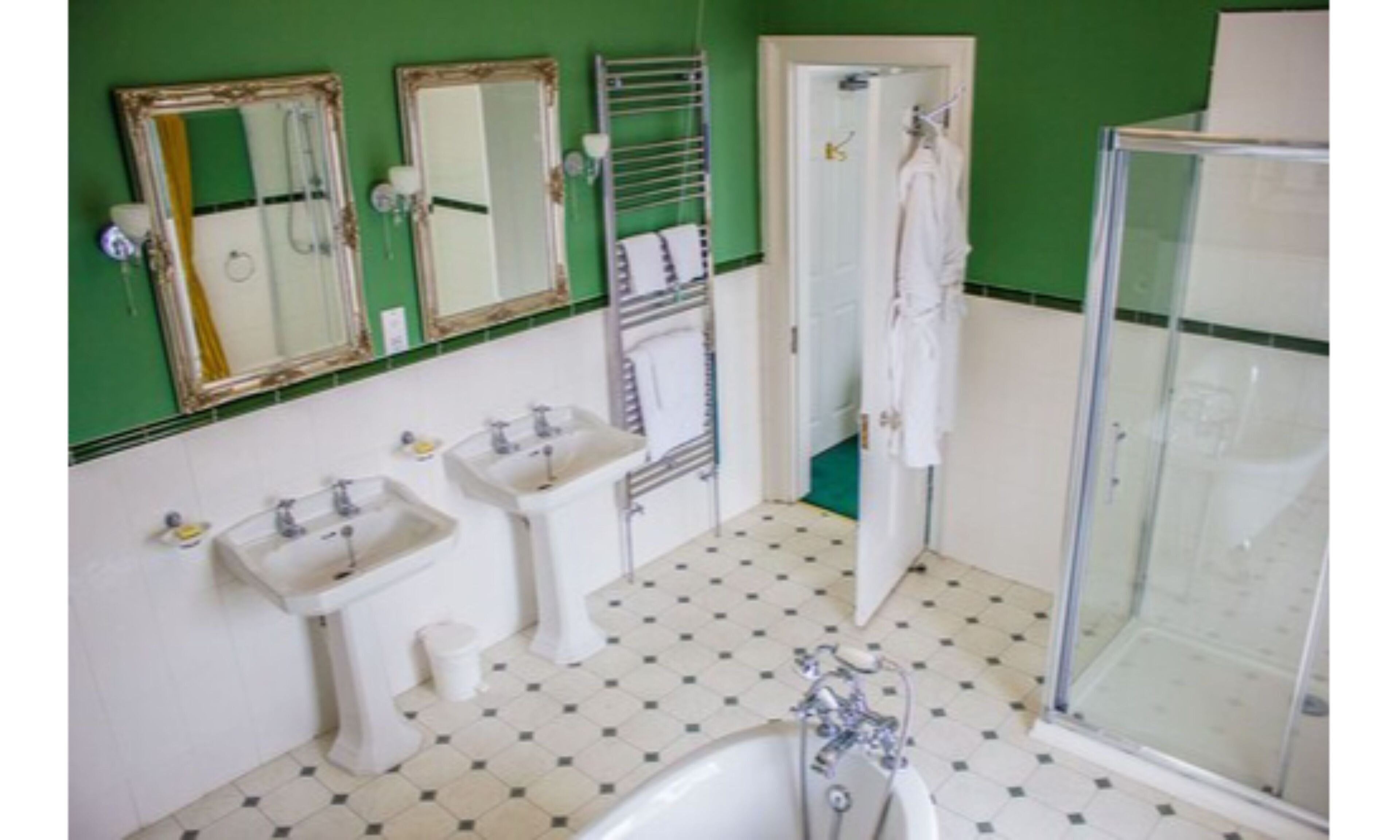 Une salle de bain avec deux lavabos, une baignoire, une douche et trois miroirs.