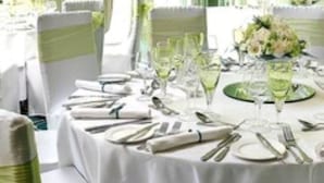 A round table set for a formal event with white tablecloths, green chair sashes, and neatly arranged cutlery. - Albert Cottage Hotel (East Cowes)