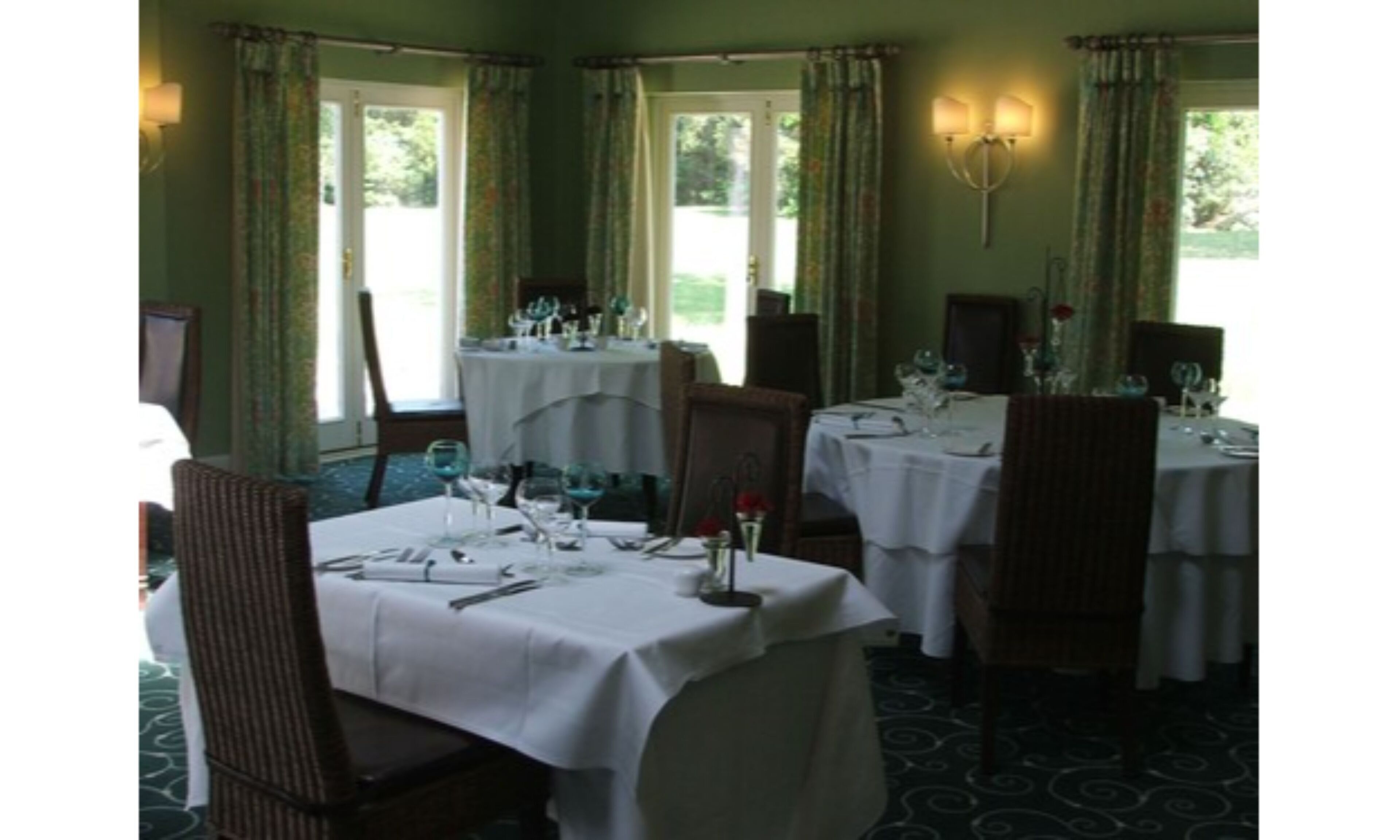 A dining area with tables set for a meal, chairs, and a chandelier.