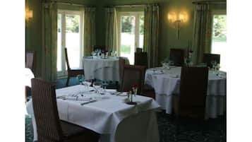 A dining area with tables set for a meal, chairs, and a chandelier.
