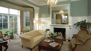 A traditional living room with a fireplace, comfortable seating, and large windows. - Albert Cottage Hotel (East Cowes)